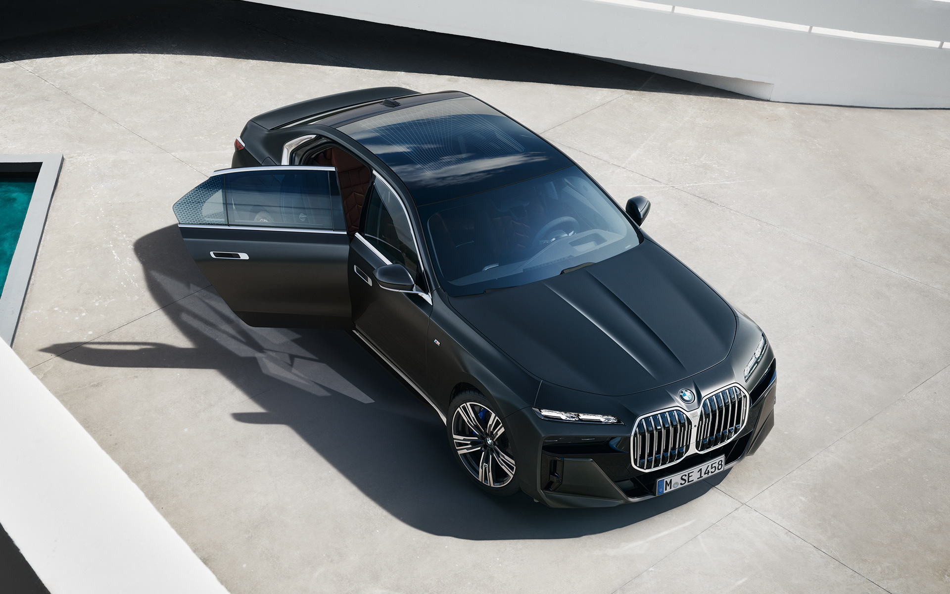 BMW 7 Serisi Sedan G70 ICE 740i M Sport donanımı, Metalik Mat Koyu Gri, yolcu kapısı açık halde üstten görünüm