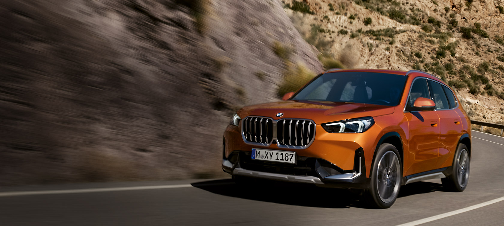 BMW X1 U11 xLine, Metalik Turuncu/Utah, Kır yolunda sürüş sırasında ön çaprazdan görünüm